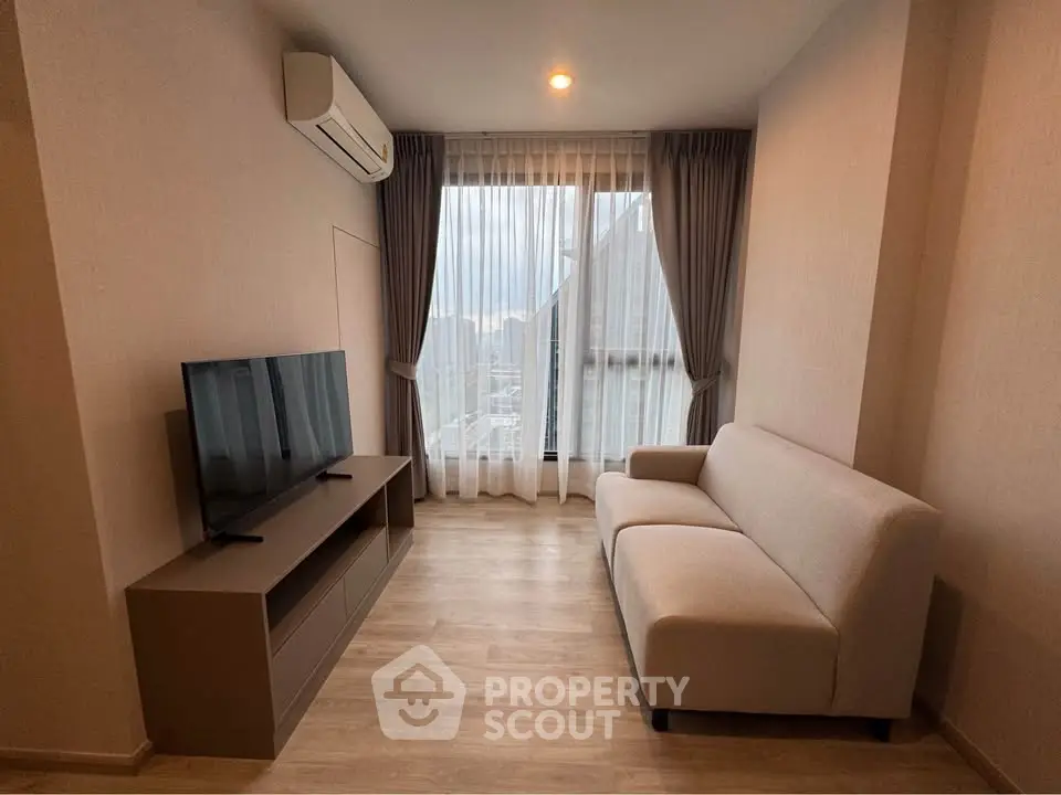 Modern living room with sleek furniture and large window offering city view