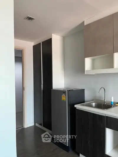 Modern kitchen with sleek cabinetry and compact fridge in a stylish apartment.