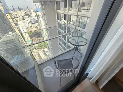 Stunning city view from a high-rise balcony with modern glass railing and cozy seating.