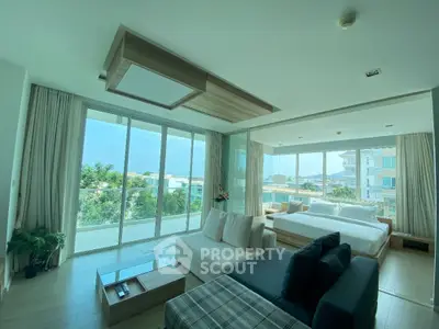Spacious modern living room with large windows and scenic view, featuring stylish furniture and natural light.