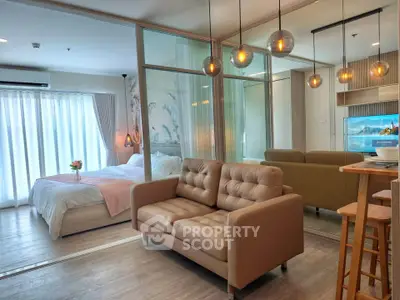 Modern studio apartment with cozy living area and stylish bedroom separated by glass partition.