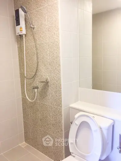 Modern bathroom with shower and toilet in a sleek tiled design.