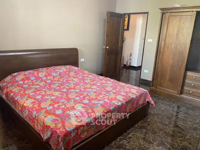 Spacious bedroom with wooden furniture and vibrant bedspread