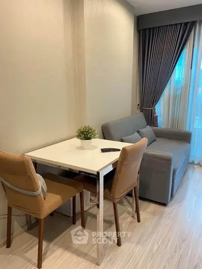 Cozy living room with modern sofa and dining table near large window with curtains.