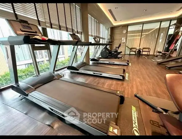 Modern gym with treadmills and large windows in upscale residential building.