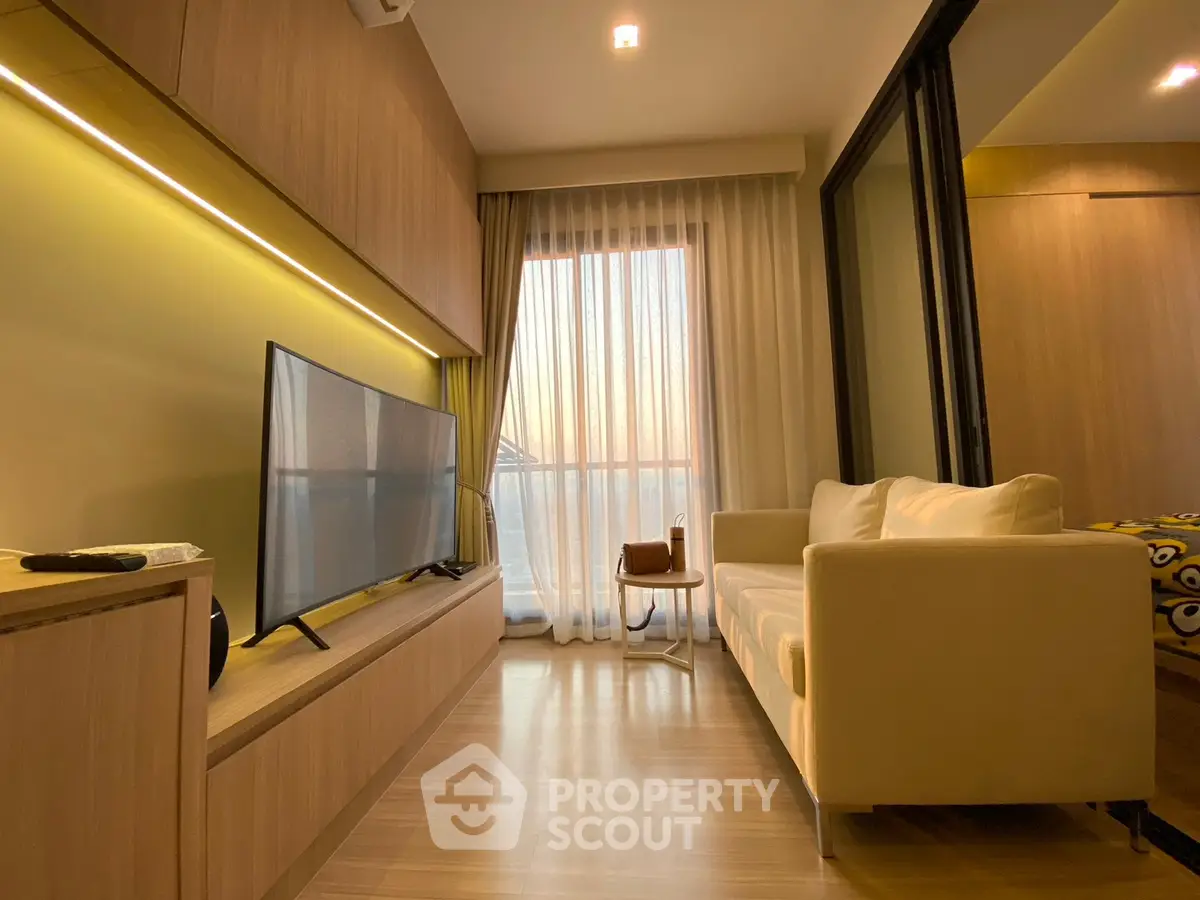 Modern living room with sleek design, featuring a large TV, cozy sofa, and floor-to-ceiling window with sunset view.