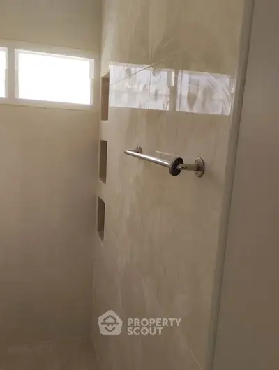 Modern bathroom with sleek tile design and natural light from high windows.