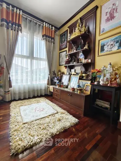Charming living room with elegant decor and wooden flooring, featuring a cozy rug and large window for natural light.
