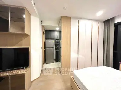 Modern bedroom with sleek design, featuring built-in wardrobe and adjacent kitchen area.