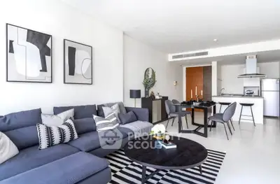 Modern living room with stylish decor and open kitchen layout, featuring a sleek sectional sofa and contemporary dining area.