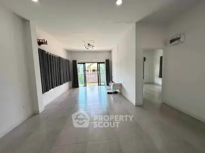 Spacious living room with large windows and modern tile flooring