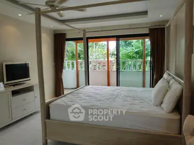 Spacious bedroom with canopy bed and balcony view of lush greenery.