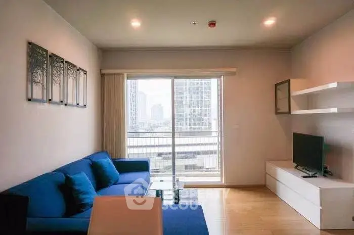 Modern living room with blue sofa and city view balcony in high-rise apartment.