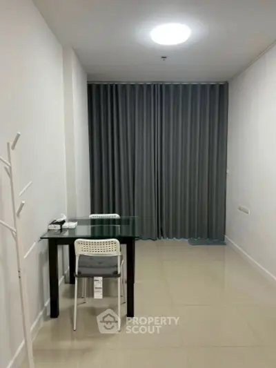 Minimalist study area with glass desk and chair, ideal for focused work in a modern apartment.