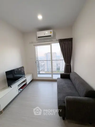 Modern living room with city view, featuring a sleek sofa and wall-mounted TV.