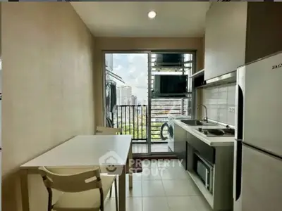 Modern kitchen with balcony view, featuring sleek appliances and dining area in urban apartment.