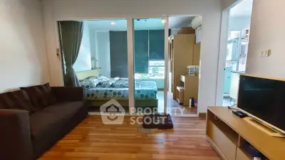 Modern apartment with cozy living room and bedroom, featuring wooden flooring and stylish furnishings.