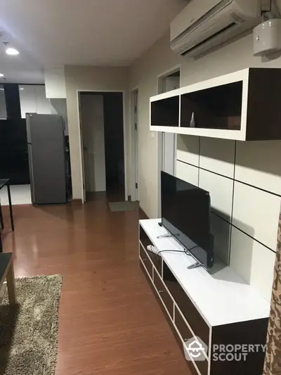 Modern living space with sleek furniture, including a wall-mounted TV unit, complemented by warm wooden flooring and a cozy area rug.