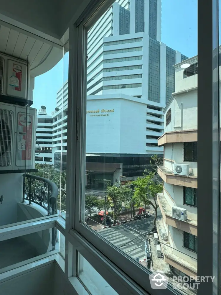 Stunning city view from modern apartment balcony with glass railing and air conditioning unit.