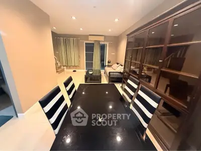 Elegant dining area with modern furniture and open layout leading to cozy living room.