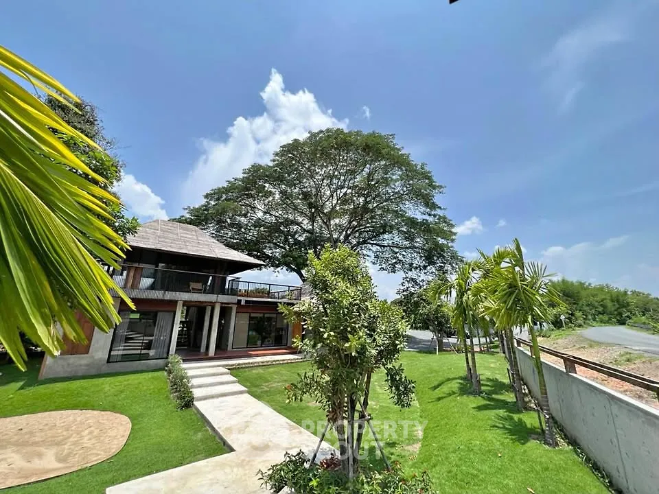 Stunning modern home with lush garden and spacious balcony under a clear blue sky.