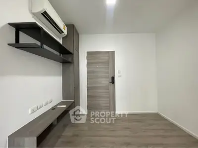 Modern minimalist living room with air conditioning and sleek wooden flooring.