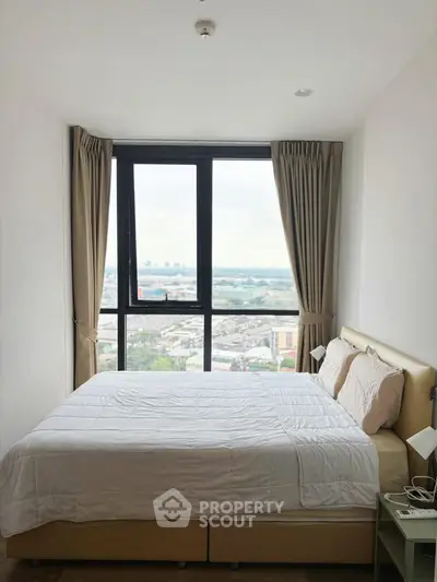 Cozy bedroom with large window offering stunning city view, perfect for relaxation and comfort.