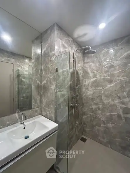Modern bathroom with sleek marble tiles and glass shower enclosure