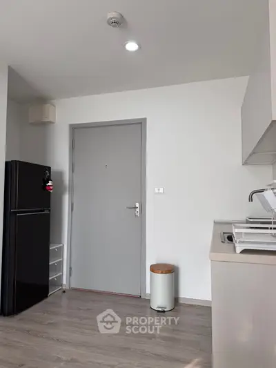 Modern kitchen with sleek design, featuring a black fridge and minimalist decor, perfect for urban living.