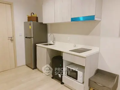 Modern kitchen with sleek cabinets, stainless steel fridge, microwave, and induction cooktop.