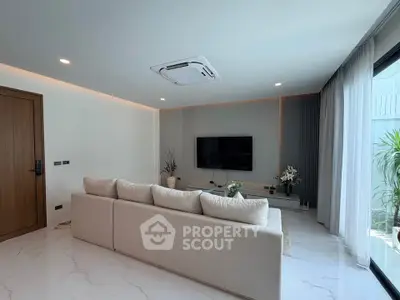 Modern living room with sleek design, featuring a large sofa, wall-mounted TV, and elegant decor.