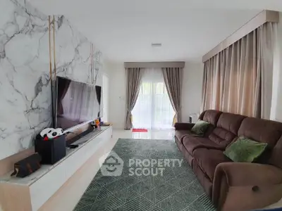 Spacious living room with modern decor and large TV, featuring elegant curtains and comfortable seating.