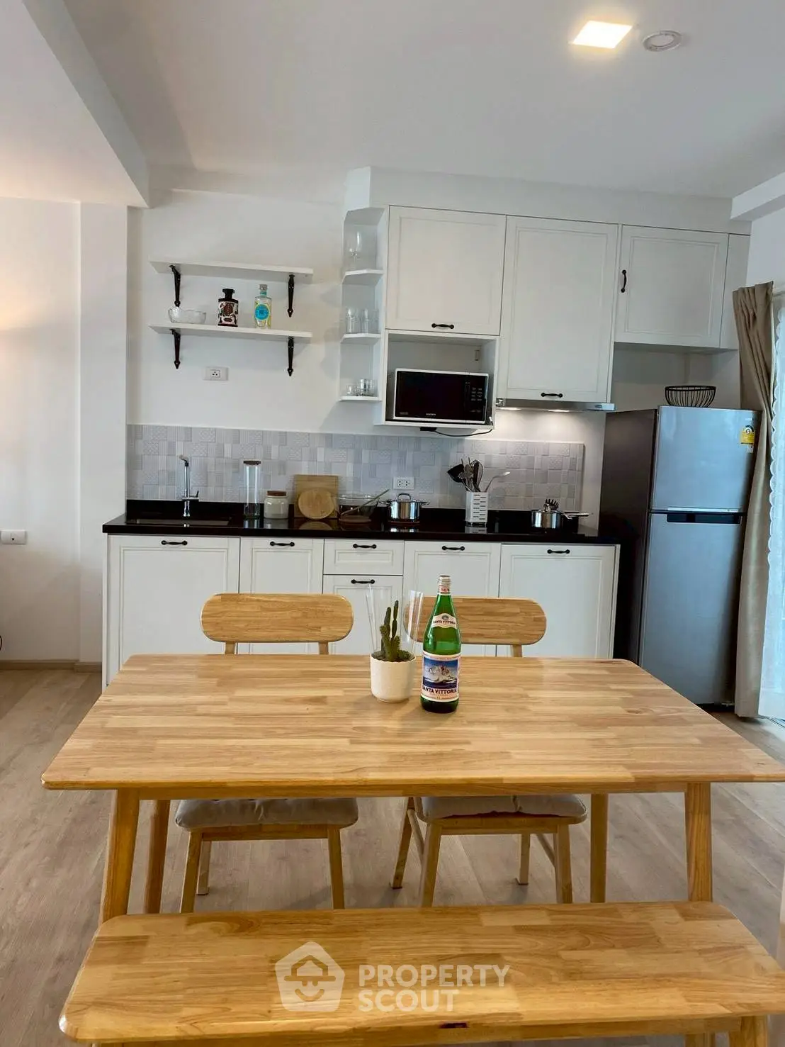 Modern kitchen with dining area featuring wooden table and chairs, sleek cabinetry, and stainless steel appliances.