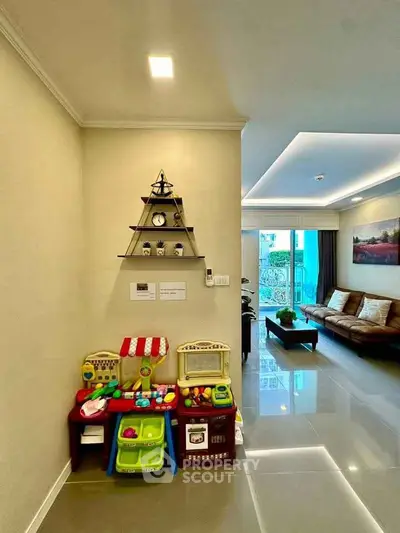 Spacious living room with elegant decor and children's play area, featuring modern furniture and bright lighting.