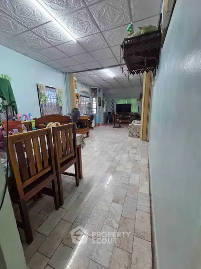 Spacious living room with tiled flooring and wooden furniture, perfect for family gatherings.