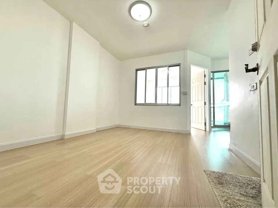 Spacious empty room with wooden flooring and bright natural light