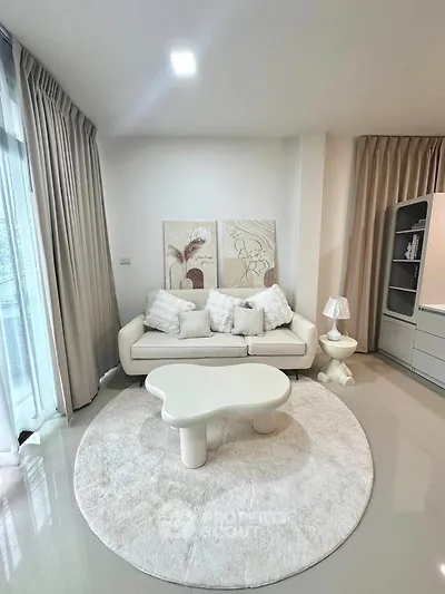 Elegant living room with modern white sofa, stylish decor, and natural light from large windows.