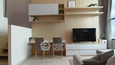 Modern living room with stylish furniture and large TV, featuring elegant shelving and natural light.