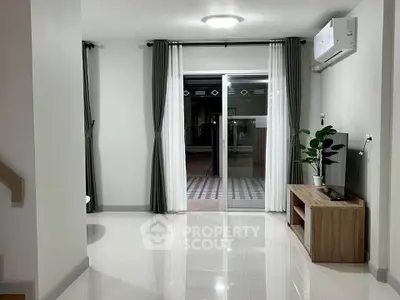 Modern living room with sleek flooring and sliding glass doors leading to a patio.