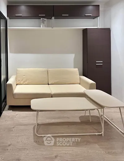 Modern living room with beige sofa and sleek coffee tables on wooden flooring.