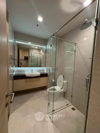 Modern bathroom with glass shower enclosure and sleek vanity in luxury apartment.