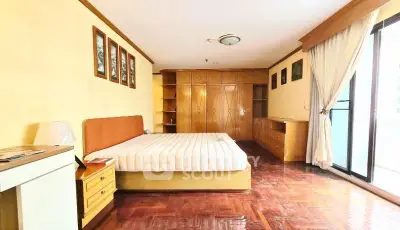 Spacious bedroom with wooden flooring and large windows for natural light.