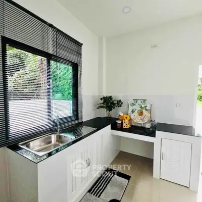 Modern kitchen with sleek countertops and large window offering natural light