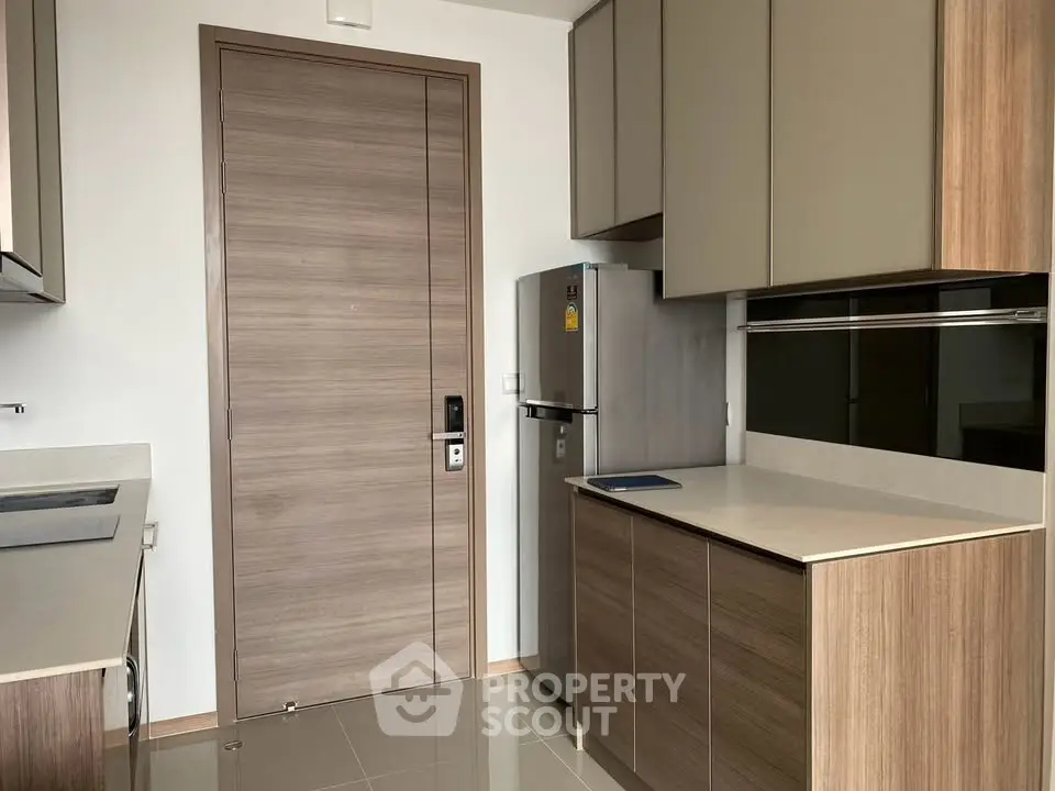 Modern kitchen with sleek cabinetry and stainless steel fridge in a contemporary apartment.