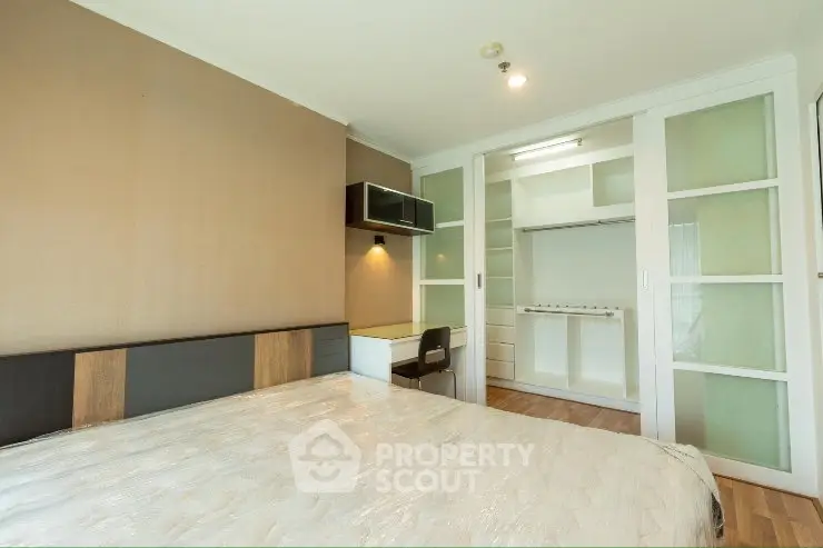 Spacious bedroom with modern design and built-in closet in a stylish apartment.