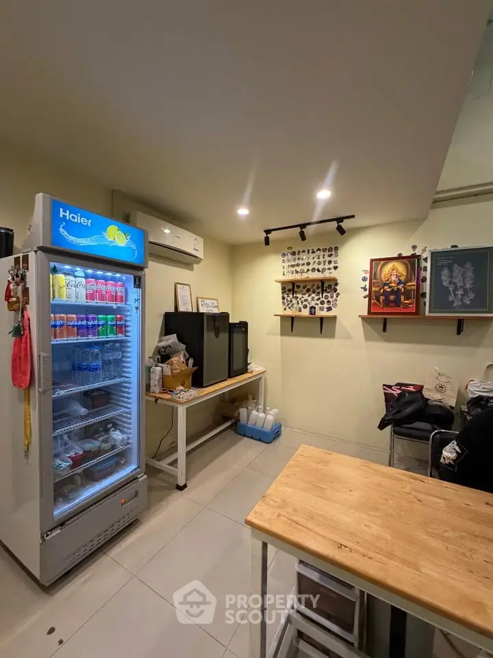 Cozy kitchen area with fridge and wooden table, ideal for small gatherings.