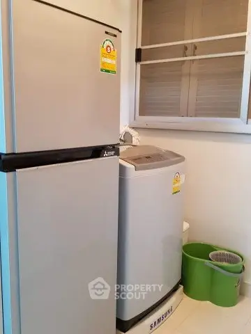 Modern kitchen with energy-efficient fridge and washing machine in compact layout.