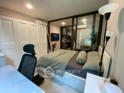 Modern bedroom with glass partition and study area, featuring sleek design and natural light.