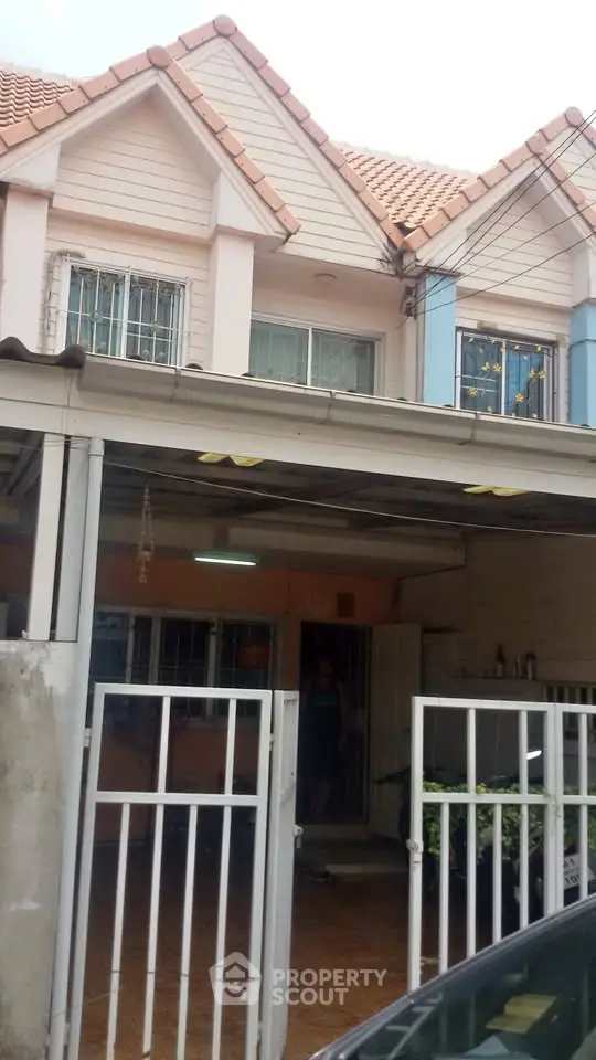 Charming townhouse with gated entrance and tiled roof in a cozy neighborhood.