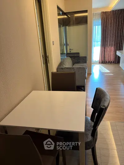 Modern apartment interior with dining area and cozy seating, featuring natural light and elegant decor.